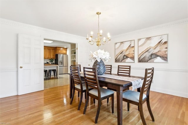 dining room featuring crown molding, light hardwood / wood-style flooring, built in features, and an inviting chandelier