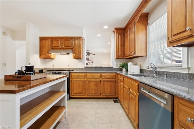 kitchen featuring appliances with stainless steel finishes, ceiling fan, dark stone counters, and sink