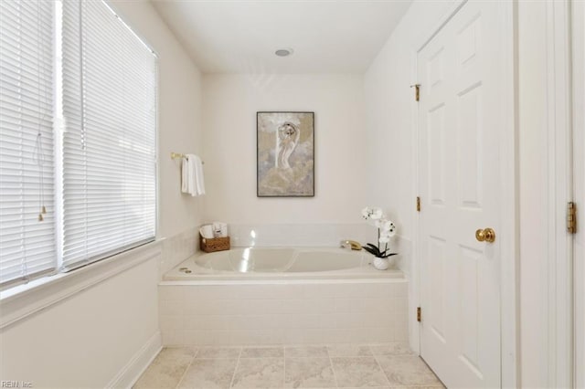 bathroom with tile patterned floors and a relaxing tiled tub