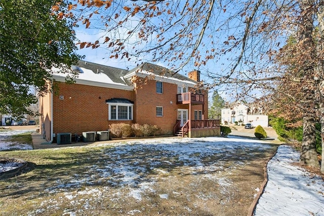 snow covered rear of property with central AC and a balcony