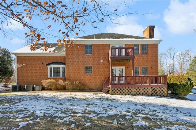 snow covered house with cooling unit, a balcony, and french doors