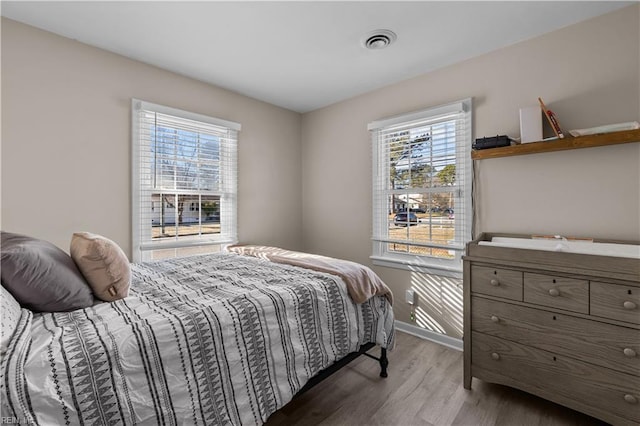 bedroom featuring wood finished floors, visible vents, and baseboards