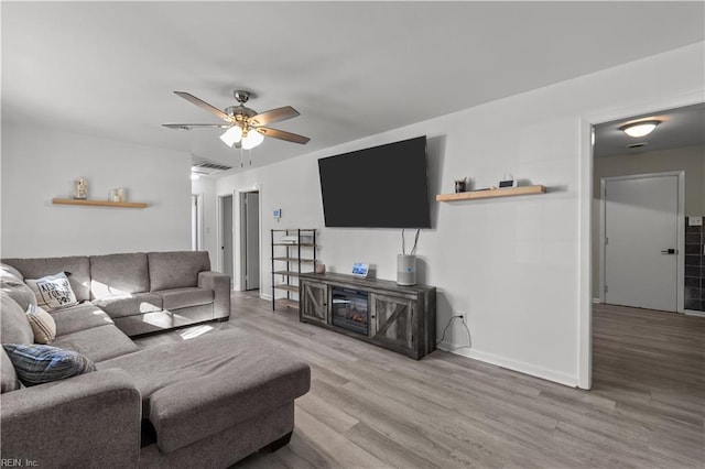 living area featuring baseboards, wood finished floors, visible vents, and ceiling fan