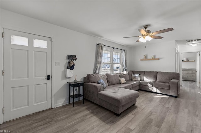 living room featuring light wood-type flooring, visible vents, and a ceiling fan