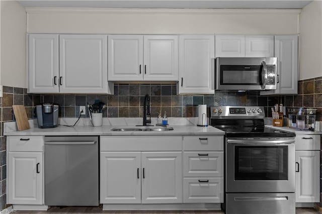 kitchen featuring tasteful backsplash, crown molding, stainless steel appliances, white cabinetry, and a sink