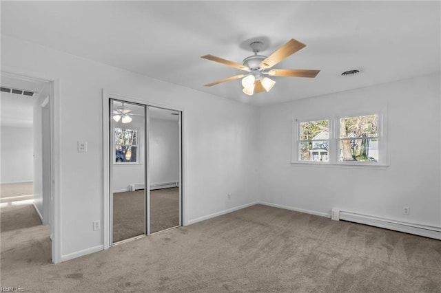 unfurnished bedroom featuring ceiling fan, a closet, light colored carpet, and a baseboard heating unit