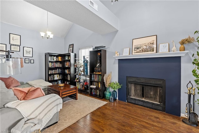 living room with dark wood-type flooring, vaulted ceiling, and an inviting chandelier