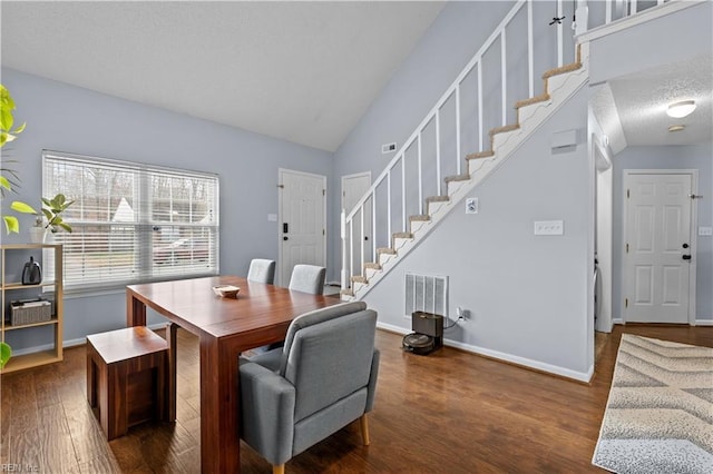 dining room featuring dark hardwood / wood-style flooring, a textured ceiling, and vaulted ceiling