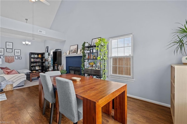 dining room with dark hardwood / wood-style flooring, high vaulted ceiling, and ceiling fan with notable chandelier