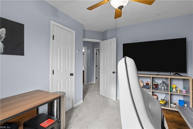 carpeted office featuring a textured ceiling and ceiling fan