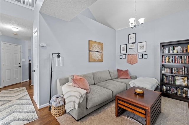 living room with hardwood / wood-style floors, a textured ceiling, vaulted ceiling, and a notable chandelier