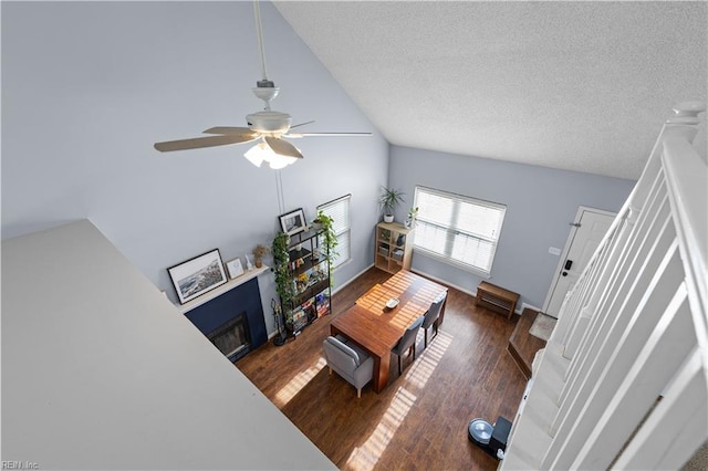 living room with a textured ceiling, dark hardwood / wood-style floors, ceiling fan, and lofted ceiling