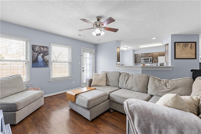 living room featuring dark hardwood / wood-style floors, ceiling fan, sink, and a textured ceiling