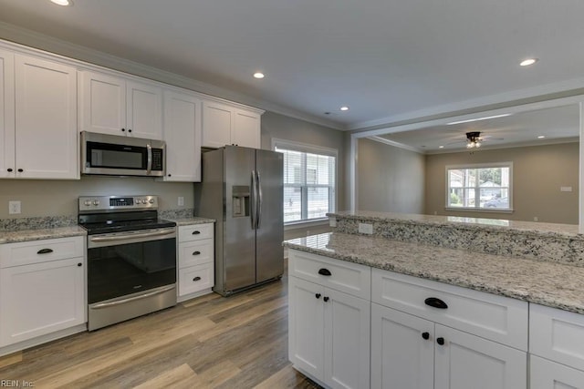 kitchen with ceiling fan, a healthy amount of sunlight, crown molding, white cabinets, and appliances with stainless steel finishes