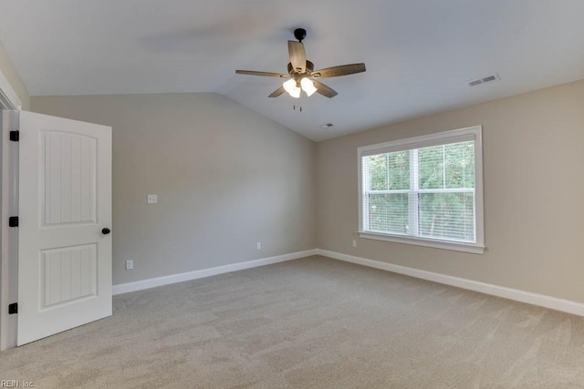 spare room with light colored carpet, vaulted ceiling, and ceiling fan