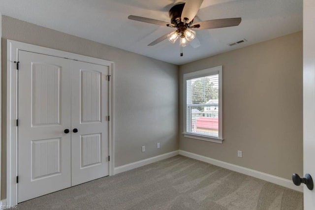 unfurnished bedroom featuring ceiling fan, a closet, and light colored carpet