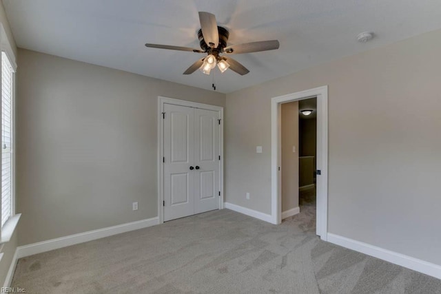 unfurnished bedroom with ceiling fan, multiple windows, light carpet, and a closet