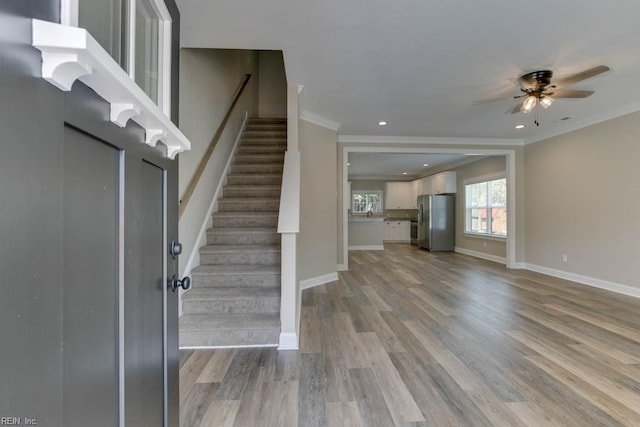 entryway with light hardwood / wood-style flooring, ceiling fan, and crown molding