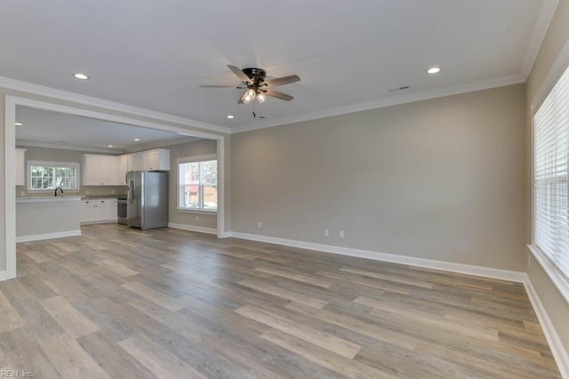 unfurnished living room with plenty of natural light, light hardwood / wood-style floors, and ornamental molding