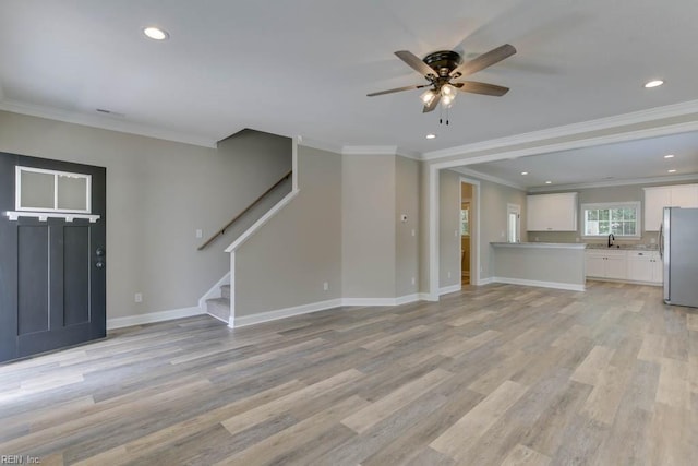 unfurnished living room featuring ceiling fan, sink, crown molding, and light hardwood / wood-style flooring