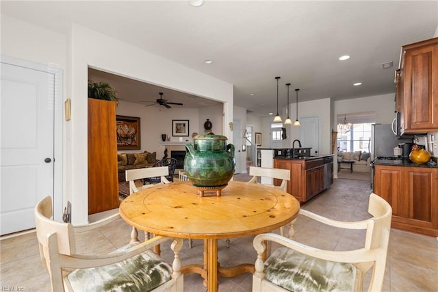 tiled dining room featuring sink and ceiling fan with notable chandelier