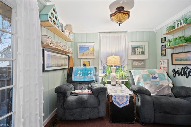 living area with crown molding and wood walls