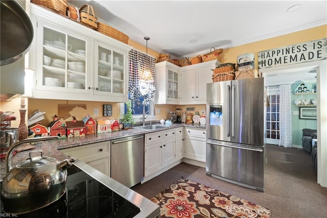 kitchen featuring ornamental molding, dark stone counters, stainless steel appliances, decorative light fixtures, and white cabinets