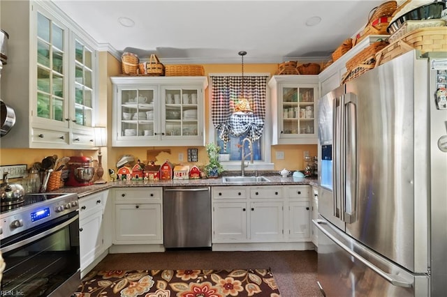 kitchen featuring stainless steel appliances, sink, pendant lighting, dark stone countertops, and white cabinets