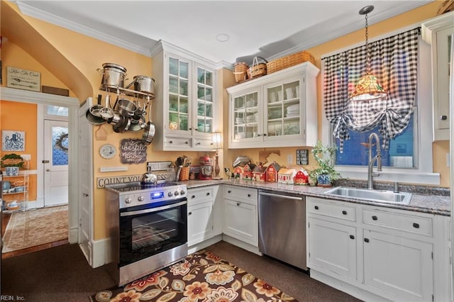 kitchen with appliances with stainless steel finishes, light stone counters, sink, pendant lighting, and white cabinets