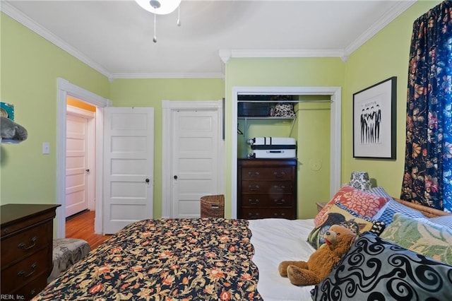 bedroom with hardwood / wood-style flooring, crown molding, and a closet