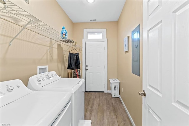 clothes washing area featuring washing machine and dryer, electric panel, and light wood-type flooring