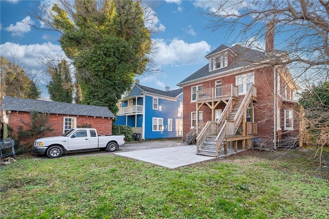 rear view of property with a yard and a balcony