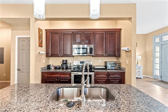 kitchen with light stone counters, sink, light wood-type flooring, and appliances with stainless steel finishes