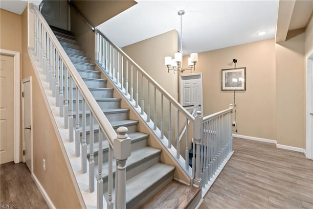 stairway featuring hardwood / wood-style floors and a chandelier