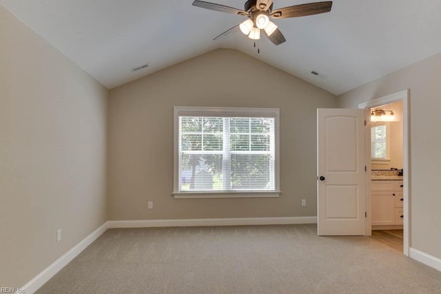 unfurnished bedroom featuring ceiling fan, vaulted ceiling, light carpet, and ensuite bath