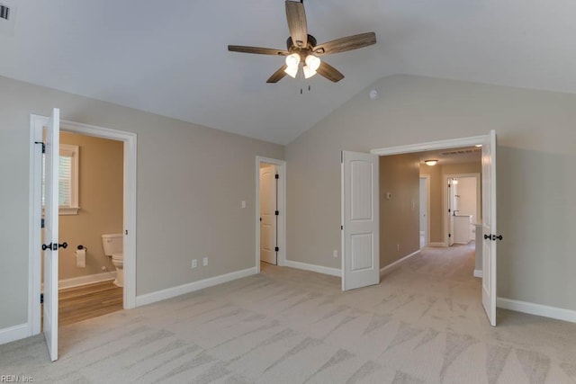 unfurnished bedroom featuring connected bathroom, light colored carpet, ceiling fan, and lofted ceiling