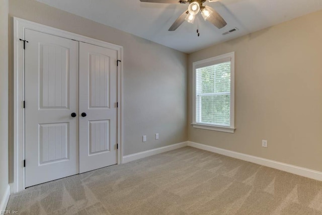 unfurnished bedroom featuring ceiling fan, light carpet, and a closet