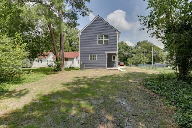 rear view of house featuring central air condition unit and a yard