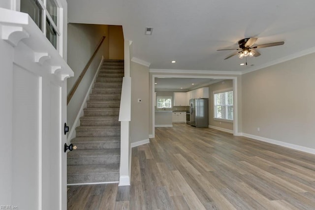 interior space with ceiling fan, crown molding, and light hardwood / wood-style floors