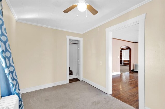 spare room featuring carpet flooring, crown molding, radiator heating unit, and ceiling fan