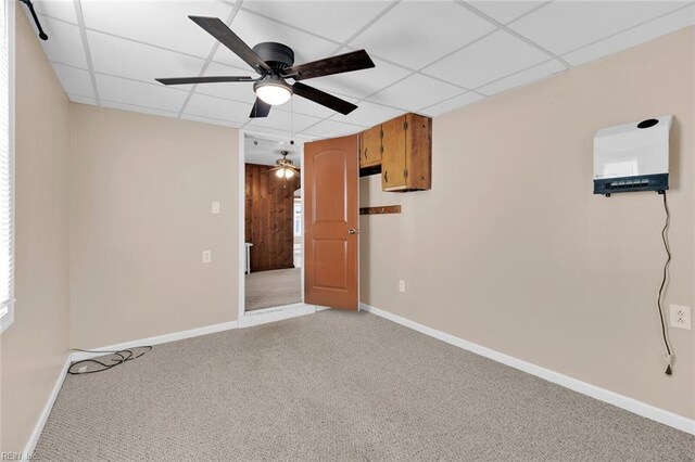 empty room with carpet flooring, ceiling fan, and a drop ceiling