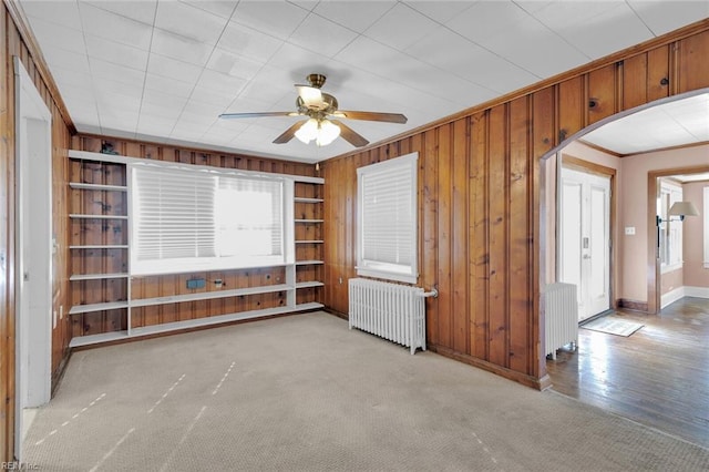 empty room featuring a healthy amount of sunlight, radiator, ceiling fan, and light carpet