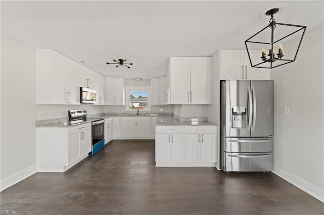 kitchen featuring white cabinets, appliances with stainless steel finishes, ceiling fan with notable chandelier, and light stone countertops