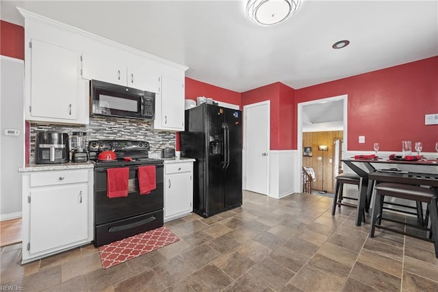 kitchen with tasteful backsplash, white cabinets, and black appliances