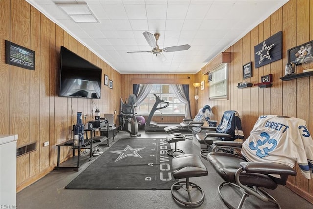 exercise area with ceiling fan, crown molding, and wood walls