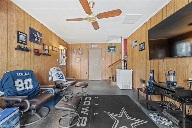 interior space with ornamental molding, concrete floors, ceiling fan, and wooden walls