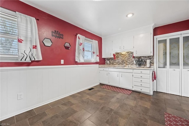 kitchen featuring white cabinets, backsplash, and sink