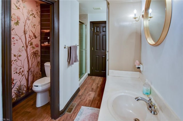 bathroom featuring wood-type flooring, vanity, toilet, and walk in shower