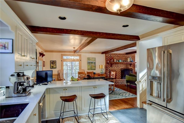 kitchen with kitchen peninsula, a kitchen bar, stainless steel appliances, and a notable chandelier