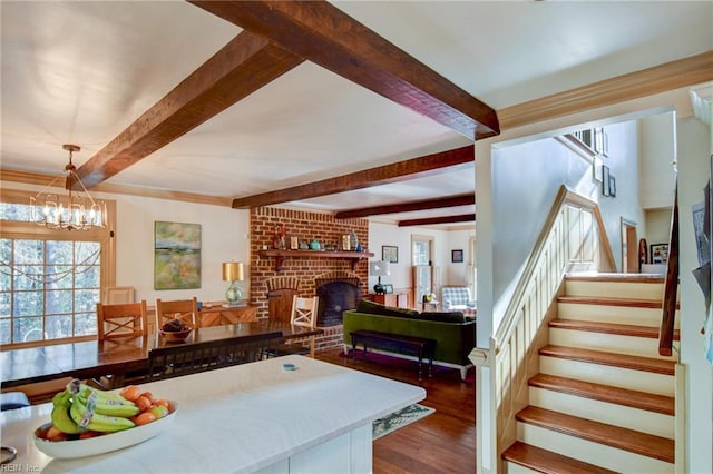 kitchen featuring hanging light fixtures, beamed ceiling, dark hardwood / wood-style floors, a chandelier, and a fireplace